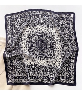 Dettaglio di un foulard in seta con motivo mandala e bordi arrotolati su velluto a coste