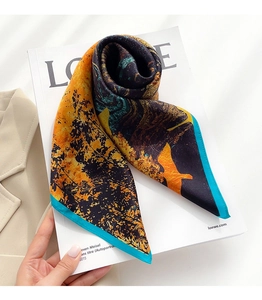 Dettaglio di un foulard in seta con motivi floreali arancioni e blu su libro di moda