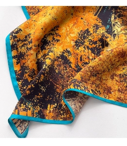 Dettaglio del foulard in seta con motivi di alberi gialli e cucitura turchese bordata