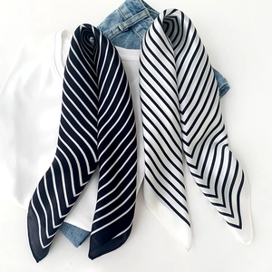 Classic black and white striped silk scarf displayed on a casual outfit set