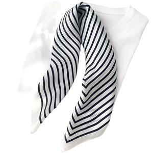 Elegant black and white striped silk scarf draped over a white t-shirt for a chic look