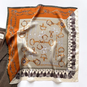 Détail du grand carré en soie avec imprimé chaînes dorées et mors sur une veste de costume