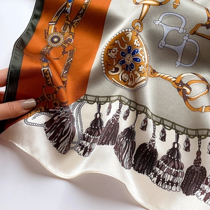 Détail d'un foulard en soie avec motif de chaîne équestre et bords roulottés main en orange