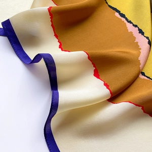 Detailed close-up showing the smooth silk texture and colorful abstract print of the scarf