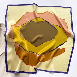 Detailed view of glossy silk square scarf with abstract patterns on a beige blazer