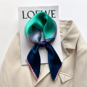 Three-color silk twilly scarf with green, lilac, and navy blue panels on a beige blazer