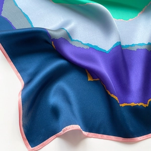 Detailed close-up of multi-color silk scarf with abstract prints and pink rolled edge finish