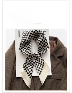 Détail d'un carré en soie à pois noirs sur fond beige avec une texture élégante