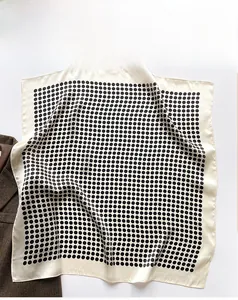 Gros plan du foulard en soie à pois sur un blazer montrant la texture douce et satinée