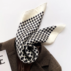 Détail d'un foulard en soie à pois drapé sur un blazer marron à chevrons pour femme