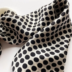 Gros plan d'un foulard en soie léger avec un motif à pois noir et blanc classique