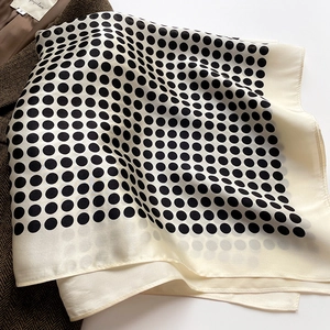 Détail d'un foulard en soie à pois plié sur un blazer en laine marron à chevrons élégant