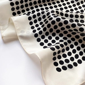 Détail d'un foulard en soie blanche à pois noirs avec une finition de couture soignée