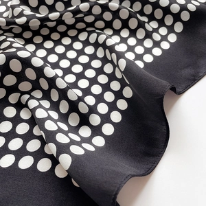 Gros plan détaillé d'un foulard en soie noir avec motif à pois blancs classiques