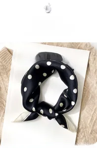 Close-up of black silk scarf with white polka dots placed on a magazine for styling