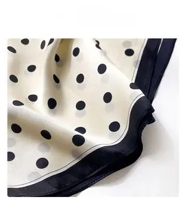 Detailed close-up of machine overlocking on a silk scarf with classic polka dot pattern
