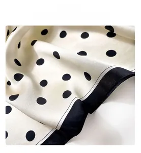 Macro view of silk scarf fabric showing smooth texture and classic black polka dot pattern