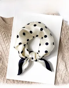 Close-up of beige silk scarf with black polka dots on a knit sweater background