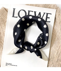 Close-up of silk scarf with classic white polka dots on black knotted on a magazine
