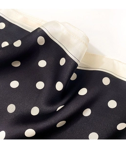 Detailed view of polka dot silk scarf featuring smooth satin texture and cream borders