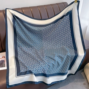Detail of luxury square scarf featuring navy blue and beige monogram chain patterns