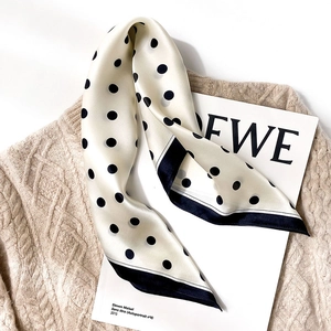 Silk-textured polka dot scarf on a cream knit sweater with minimalist vintage style