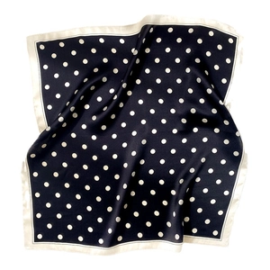 Classic black and white polka dot silk scarf with cream border, elegantly flat-laid