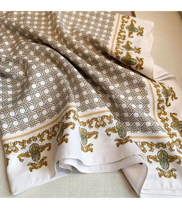 Detail of baroque silk scarf featuring golden scroll patterns and satin fabric texture