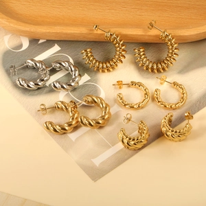 Set of 18K gold plated and silver twisted C-shape stud earrings on wooden tray