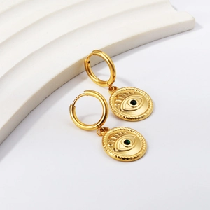 Boucles d'oreilles Evil Eye dorées avec pierre verte sur présentoir blanc