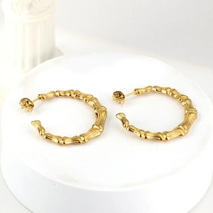 18K gold plated C-shaped bamboo texture hoop earrings on white display pedestals