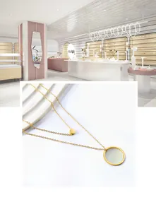 Detail of 18K gold double-layer necklace featuring a small disc and a large ring pendant