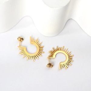 Boucles d'oreilles dorées semi-circulaires en forme de C sur fond minimaliste blanc