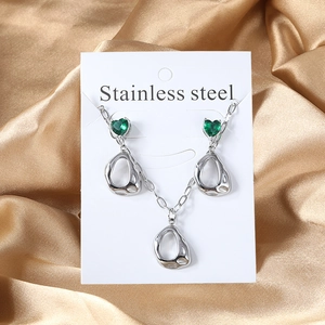 Detailed shot of stainless steel jewelry set with green heart stones on satin background