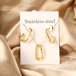 Close-up of gold stainless steel jewelry set with heart liquid metal texture on silk