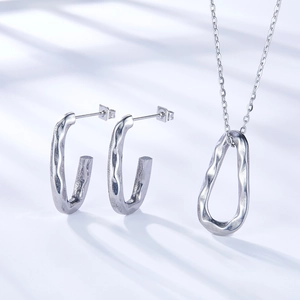 Close-up of silver stainless steel jewelry set with unique hammered texture and C-shape design