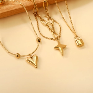 Gold stainless steel bracelet set with heart, lock, and star charms on beige background