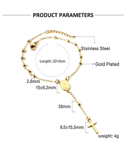Detalle macro de pulsera de cuentas de acero dorado con colgantes de cruz y medalla