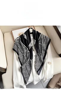 Detailed close-up of a black and white paisley print silk scarf draped on a white blouse