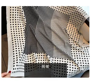 Detail of black and white geometric print silk scarf laid on light furniture