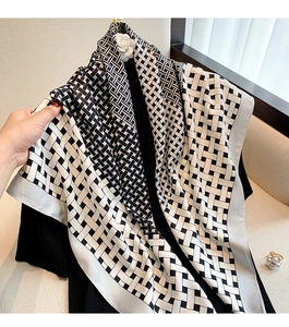Detail of soft silk-like scarf featuring geometric weave patterns and elegant light gray border