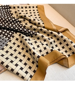Detail of geometric pattern scarf with silk texture and contrasting brown border