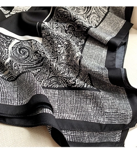 Close-up of black and white paisley silk scarf with elegant geometric pattern and twill texture