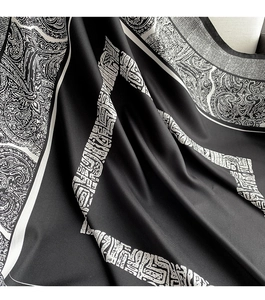 Detailed view of silk satin scarf featuring white paisley patterns on black fabric