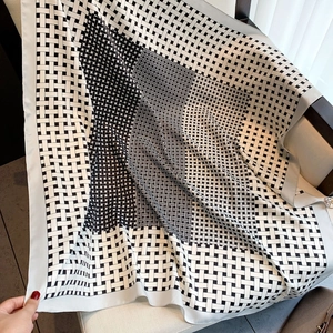Classic black and white geometric grid silk square scarf draped on a wooden chair