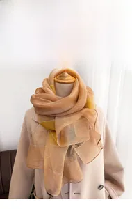 Detail of soft silk blend scarf in ginger yellow and light champagne on mannequin