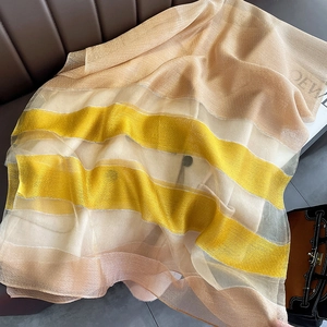 Detail shot of silk-blend scarf featuring yellow and champagne gold stripes with logo