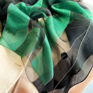 Detail view of green and black striped scarf with shimmering gold lurex metallic threads