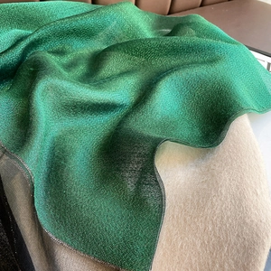 Detailed texture of emerald green silk blend scarf with subtle metallic shimmer and wavy edges