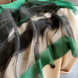 Detail of silk blend shawl featuring black-green gradient colors and silver lurex stripes